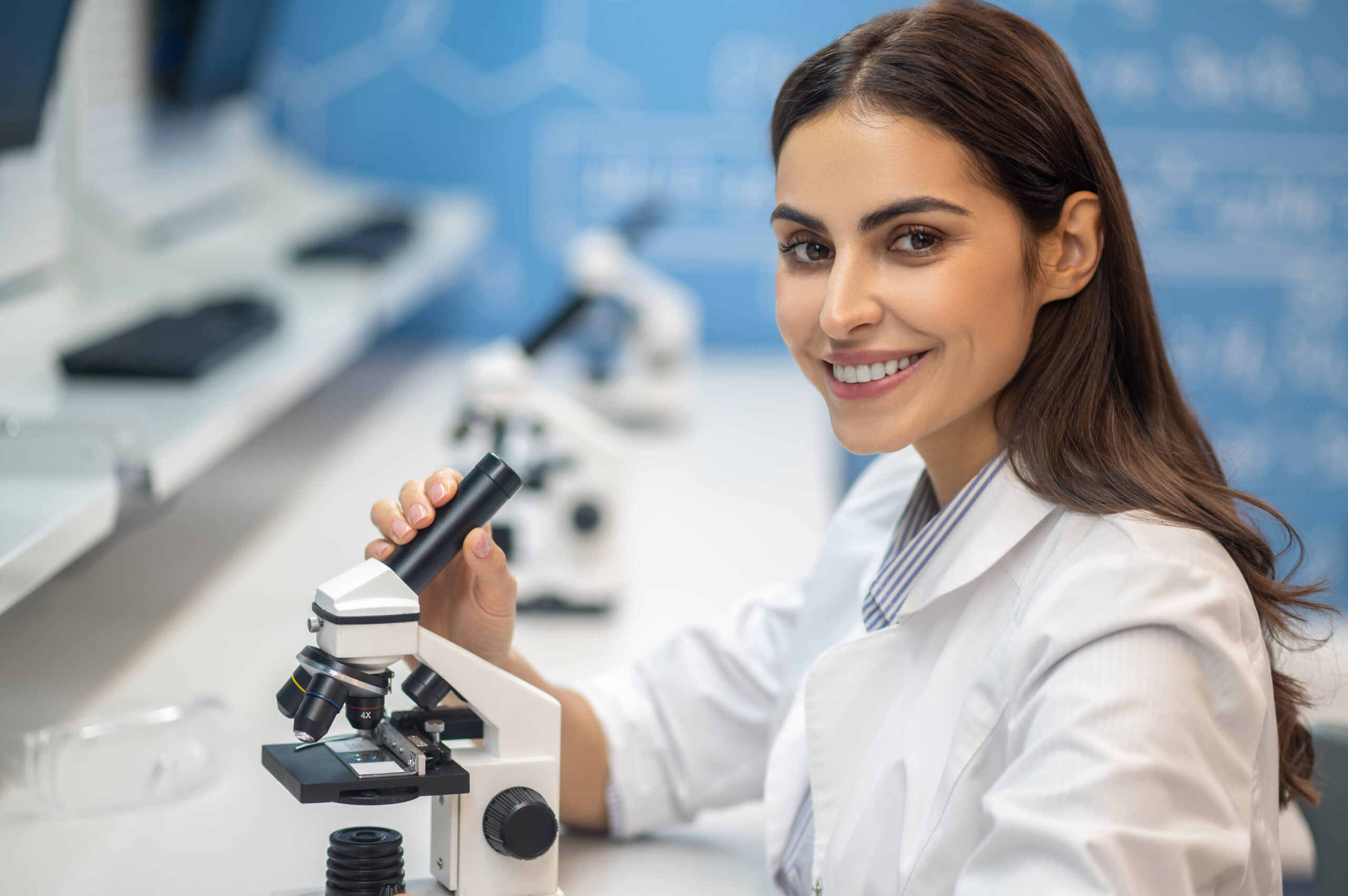 Happy woman near microscope looking at camera