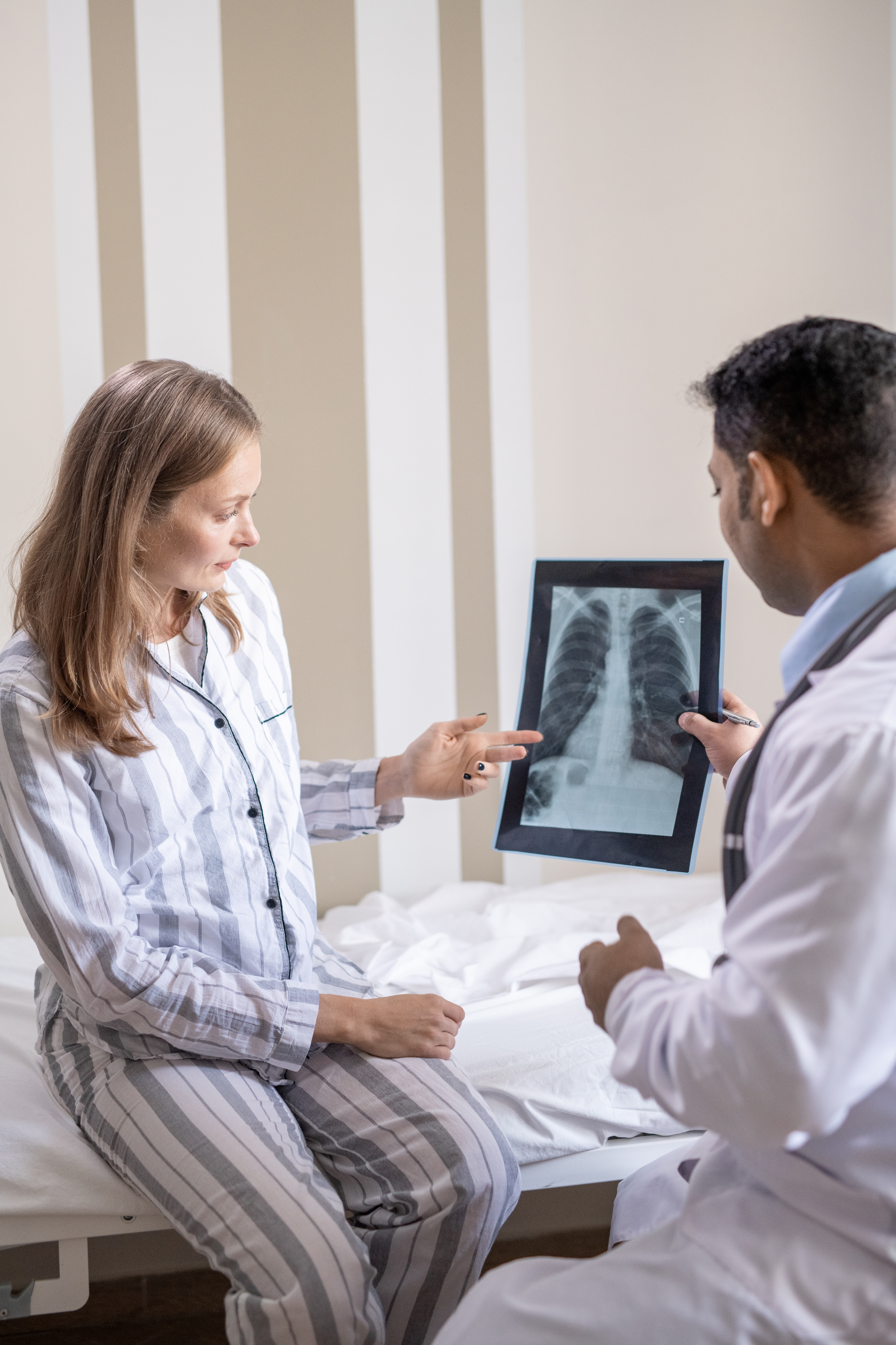 Patient sitting on bed in front of her doctor during discussion of x-ray results